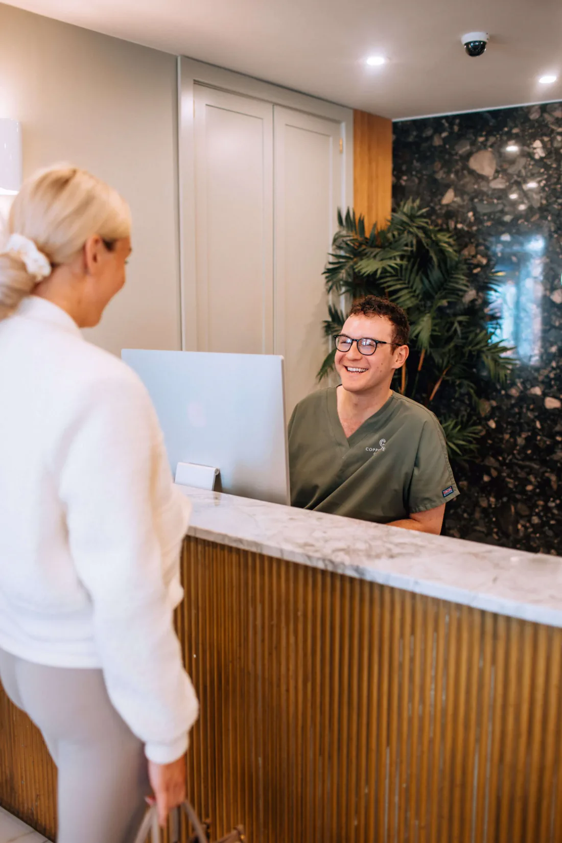 A patient is welcomed at the reception desk of the Coppergate Clinic in York.