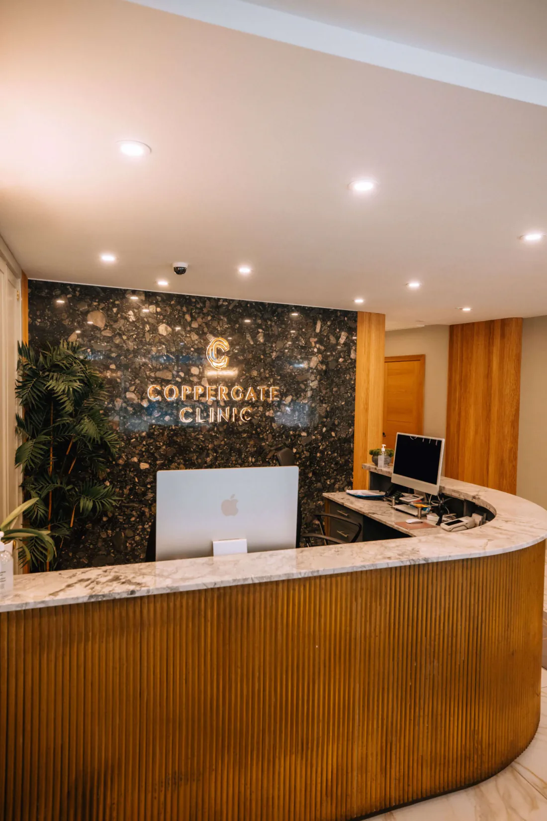The reception desk at the Coppergate Clinic in York, the clinic name on a dark marble wall.