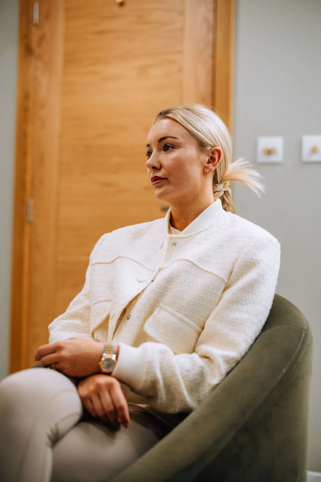 A woman sitting in an armchair at the clinic, listening.