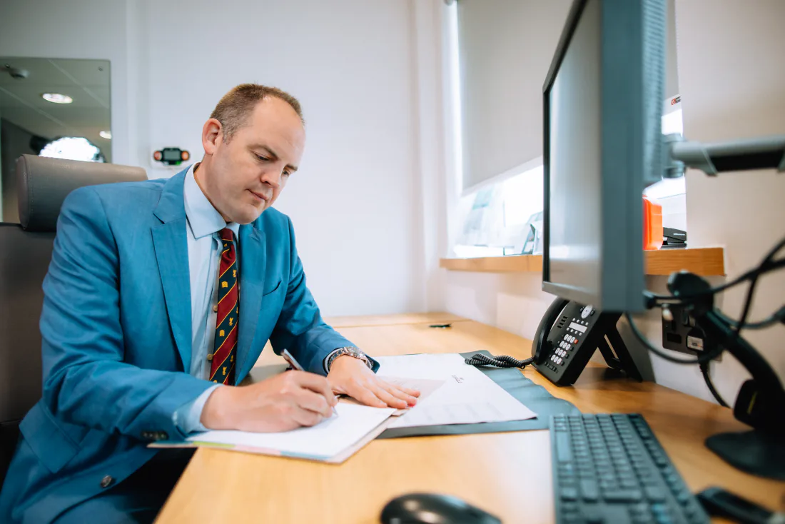 Mr Christopher West at his desk in clinic, writing up notes.
