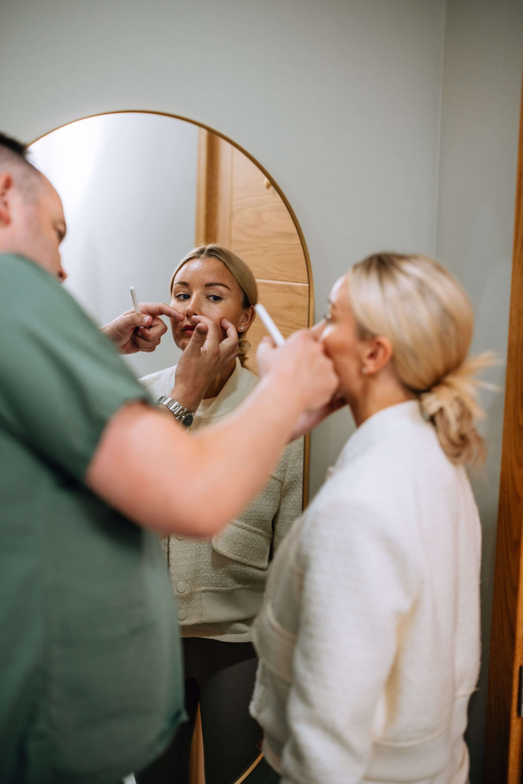Mr West holding a pen to a woman’s face in front of a mirror