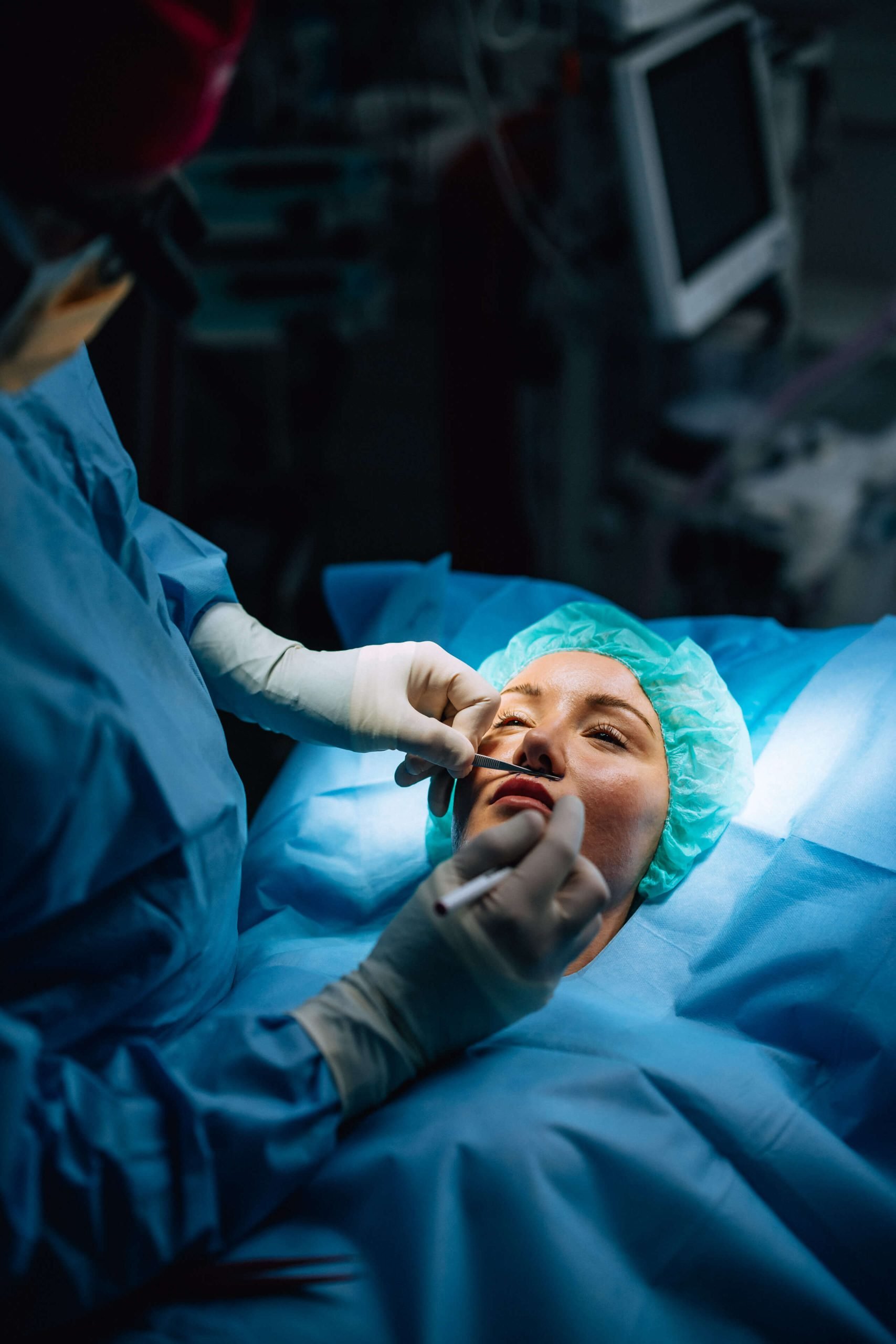 A gloved surgeon with a pen at the face of a woman lying on an operating table